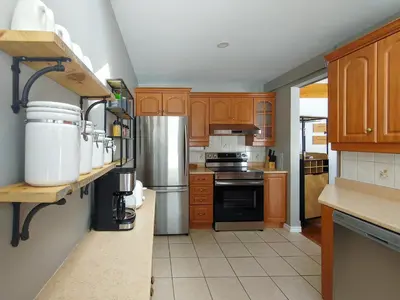 a kitchen with wooden cabinets and a stainless steel refrigerator at Chalet Évasion Orford in Orford