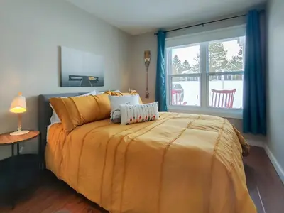 a bedroom with a bed with yellow sheets and a window at Chalet Évasion Orford in Orford