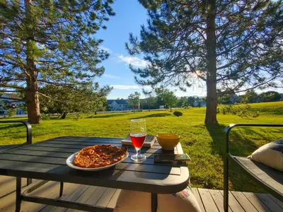 a picnic table with a pizza and a glass of wine at Chalet Évasion Orford in Orford