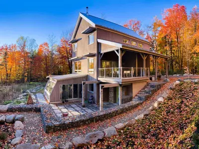 a large house on a hill in the woods at Le Camp Caché Shefford in Shefford