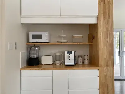 a kitchen with white cabinets and white appliances at Le Camp Caché Shefford in Shefford