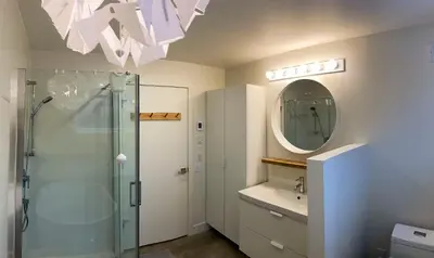 a bathroom with a shower and a sink and a mirror at Le Camp Caché Shefford in Shefford