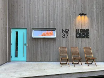 a pair of chairs sitting in front of a building at Le Camp Caché Shefford in Shefford