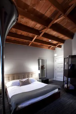 a bedroom with a large bed and wooden ceilings at Le Pleasant Hôtel & Café in Sutton