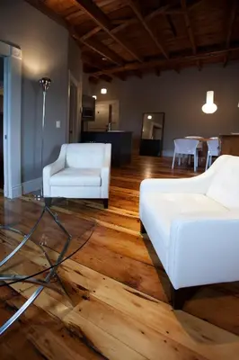 a living room with two white couches on a wooden floor at Le Pleasant Hôtel & Café in Sutton