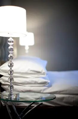a glass table with a lamp on top of a bed at Le Pleasant Hôtel & Café in Sutton