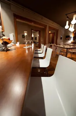 a dining room with a long table and white chairs at Le Pleasant Hôtel & Café in Sutton