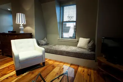 a living room with a couch and a chair and a window at Le Pleasant Hôtel & Café in Sutton