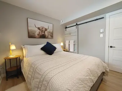 a bedroom with a bed and a picture of a cow at Chalet Escapade Orford in Orford