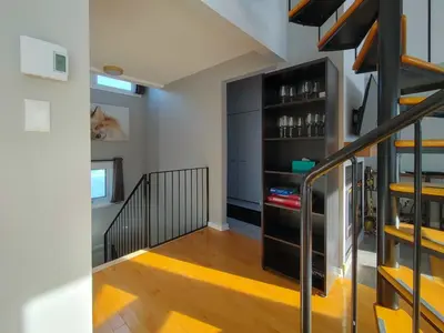 a room with a staircase with a shelf of wine bottles at Chalet Escapade Orford in Orford