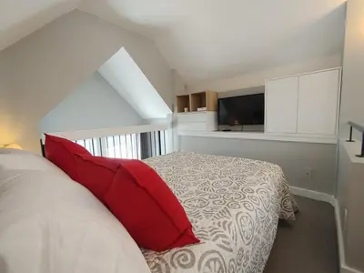 a bedroom with a bed with red pillows and a tv at Chalet Escapade Orford in Orford