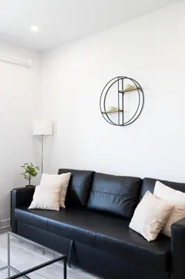 a black leather couch in a living room with a mirror at Le Mile End by M11 - Neat & Spacious 1BDR Unit in Montréal