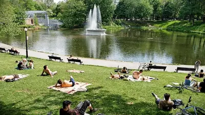 a group of people laying in the grass near a pond at Le Mile End by M11 - Neat & Spacious 1BDR Unit in Montréal