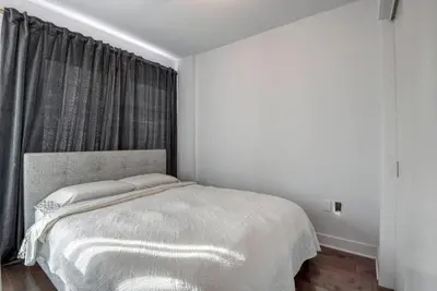 a white bedroom with a bed with a window at 2 bedroom Condo in the heart of the city Montreal in Montréal