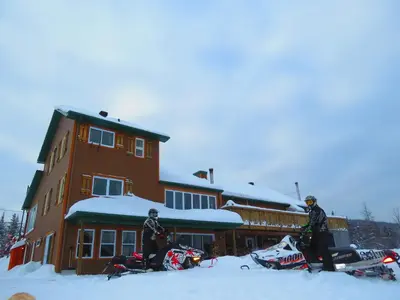 two people standing in the snow in front of a building at Le Gîte Ambrelane in Thetford Mines