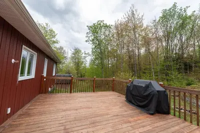 a large wooden deck on a red house at Chalet in a dark sky reserve in Notre-Dame-Des-Bois