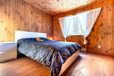 a bedroom with a bed in a wooden wall at Chalet in a dark sky reserve in Notre-Dame-Des-Bois