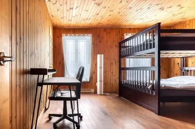 a bedroom with a bunk bed and a desk and a chair at Chalet in a dark sky reserve in Notre-Dame-Des-Bois