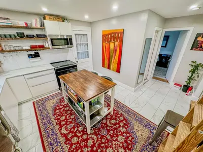 a kitchen with a wooden table on a red rug at Barel Residence Homestay in Longueuil