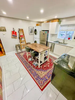 a kitchen with a wooden table and chairs on a rug at Barel Residence Homestay in Longueuil