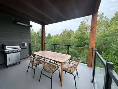 a wooden table and chairs on a deck with a stove at Le Joford in Orford