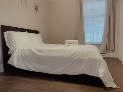 a bedroom with a bed with white sheets and a window at Spacieux Appartement de 3 Chambres downtown in Montréal