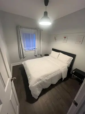 a bedroom with a bed with white sheets and a window at Spacieux Appartement de 3 Chambres downtown in Montréal