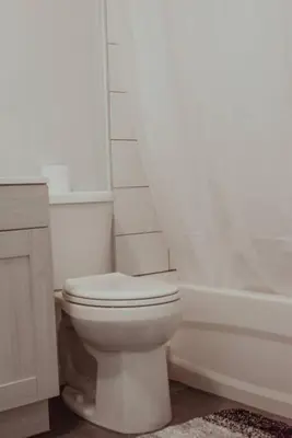 a white bathroom with a toilet and a bath tub at Spacieux Appartement de 3 Chambres downtown in Montréal