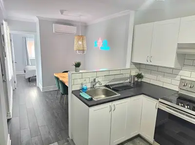 a kitchen with white cabinets and a sink and a table at Spacieux Appartement de 3 Chambres downtown in Montréal