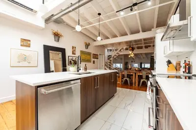 a kitchen with wooden cabinets and white counter tops at North House - Stunning Old Montreal Penthouse in Montréal
