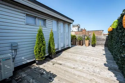 a wooden walkway next to a house with potted plants at North House - Stunning Old Montreal Penthouse in Montréal