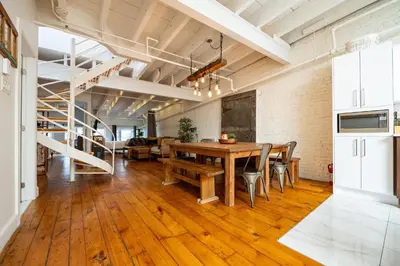 a dining room with a wooden table and a staircase at North House - Stunning Old Montreal Penthouse in Montréal