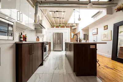an open kitchen with wooden cabinets and a long hallway at North House - Stunning Old Montreal Penthouse in Montréal