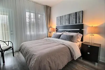 a bedroom with a large bed and a chair at LeChamplain #206 CITQ#248275 in Bromont