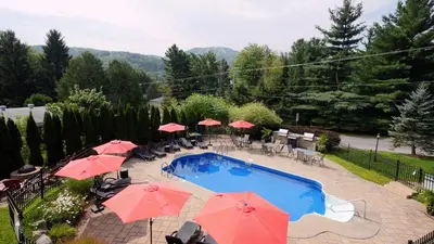 a swimming pool with umbrellas and tables and chairs at LeChamplain #206 CITQ#248275 in Bromont