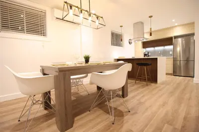 a kitchen and dining room with a wooden table and white chairs at Luxueux - Deco moderne, Rosemont in Montréal