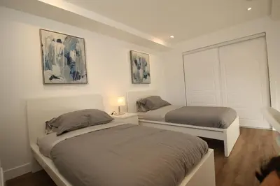 a bedroom with two beds and a white door at Luxueux - Deco moderne, Rosemont in Montréal