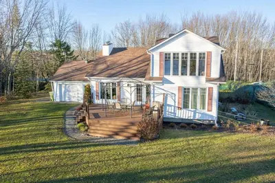 a house with a large deck in the yard at Chalet BIA - Cap au Sud in Trois-Lacs