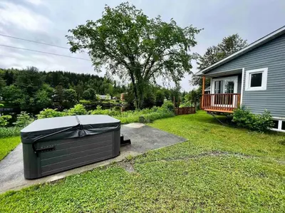 a backyard with a hot tub sitting in the grass at Chalet BIA - Au courant des 2 rivières in Weedon-Centre