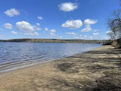 a body of water with a sandy shore with clouds at Chalet BIA Foyer & Spa in Trois-Lacs