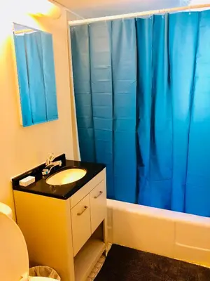 a bathroom with a sink and a blue shower curtain at Stylish Montreal Apartment: Comfortable Stay in the Golden Square Mile in Montréal