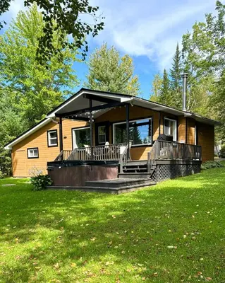 a log cabin with a large porch and green grass at Chalet Le Shack O2 in Stratford