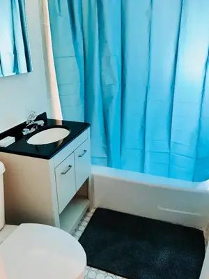 a bathroom with a sink and a blue shower curtain at Stylish Montreal Apartment: Comfortable Stay in the Golden Square Mile in Montréal