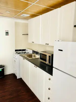a white kitchen with a sink and a microwave at Stylish Montreal Apartment: Comfortable Stay in the Golden Square Mile in Montréal