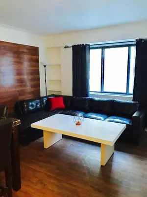 a living room with a black leather couch and a coffee table at Stylish Montreal Apartment: Comfortable Stay in the Golden Square Mile in Montréal