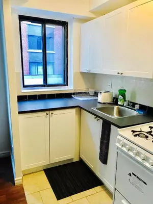 a kitchen with white cabinets and a sink and a window at Stylish Montreal Apartment: Comfortable Stay in the Golden Square Mile in Montréal