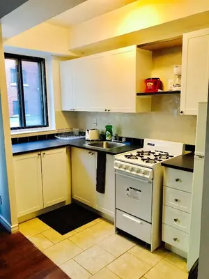 a kitchen with white cabinets and a stove top oven at Stylish Montreal Apartment: Comfortable Stay in the Golden Square Mile in Montréal