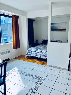 a bedroom with a bed and a table and a window at Stylish Montreal Apartment: Comfortable Stay in the Golden Square Mile in Montréal