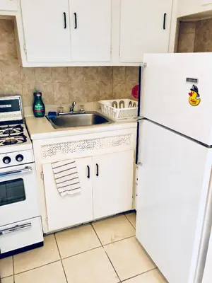 a white kitchen with a sink and a refrigerator at Stylish Montreal Apartment: Comfortable Stay in the Golden Square Mile in Montréal