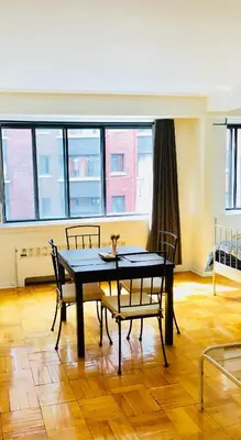 a dining room with a table and chairs and windows at Stylish Montreal Apartment: Comfortable Stay in the Golden Square Mile in Montréal